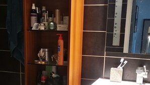 A bathroom with a wooden vanity, a mirror, and a shelf with toiletries. - 1 bedroom apt. of an Artist photographer close to Cannes Croisette (Cannes)