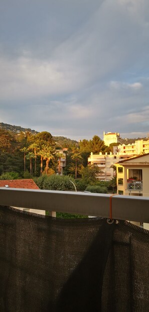 Uma varanda com vista para uma encosta, edifícios e árvores.