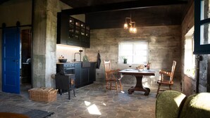 A rustic interior with a stone floor, wooden furniture, and a kitchen area. - Jakob's old Farmhouse (Rangárþing eystra)