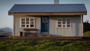 A small, single-story house with a metal roof, two large windows, and a front door. - Jakob's old Farmhouse (Rangárþing eystra)