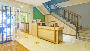 A reception area with a wooden counter, a staircase, and a green wall.
