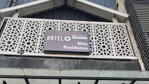 A hotel with a sign for 'HOTELO Elite Residence' and a 'Self Service Laundry' available 24 hours.