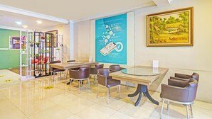 A hotel lobby with a reception desk, seating area, and a large informational poster.