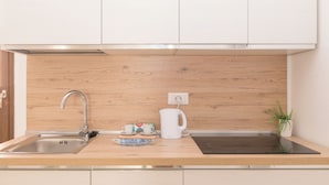 A modern kitchen with a stainless steel sink, wooden countertop, and white cabinets. - Appartamento Mirto In The City Center (Santa Teresa di Gallura)
