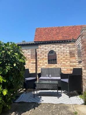 Sit and relax in the charming outdoor seating area with a pair of wicker chairs and a small table.