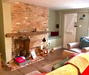 Cozy living room with a fireplace, sofa, and side table, creating a welcoming atmosphere.