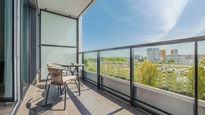 A balcony with a table and chairs, a view of a cityscape with buildings and trees. - Apartamenty Sun&Snow Baltea (Gdansk)