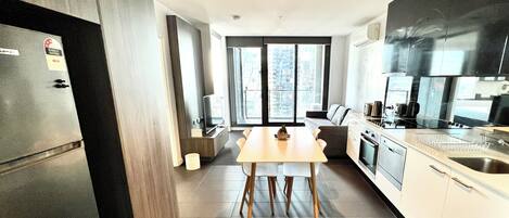 A modern kitchen with a dining area, large windows, and a view of the city.