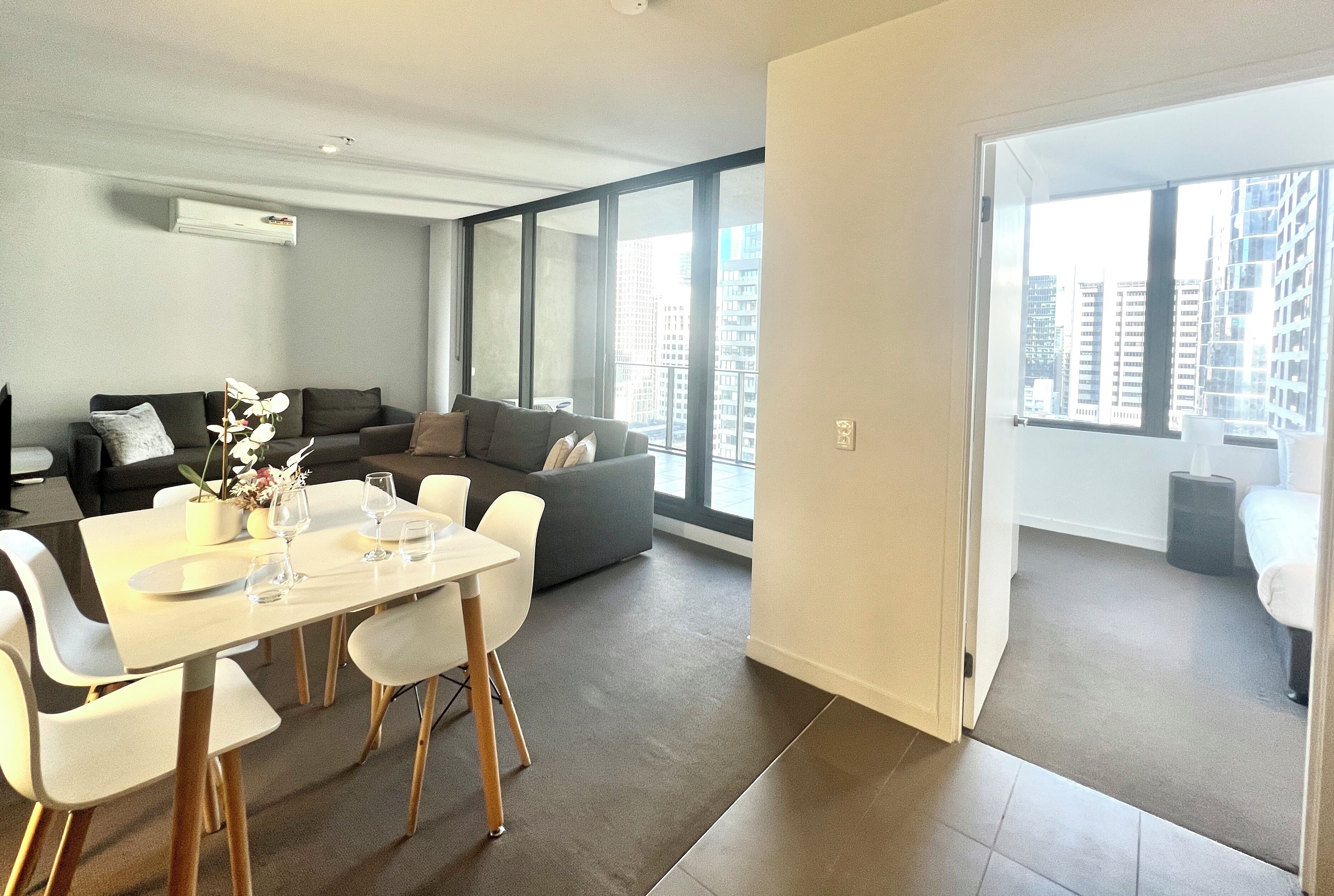 A modern living room with a dining area, large windows, and a view of the city.