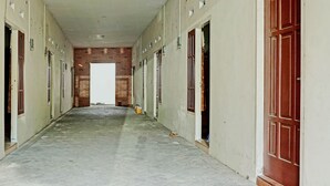 A corridor with doors on both sides, leading to a room with a wooden door at the end. - OYO Life  92393 Namimart Syariah 1 (Kediri)