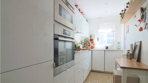 Een moderne keuken met witte kasten, een ingebouwde oven en een betegelde spatwand.