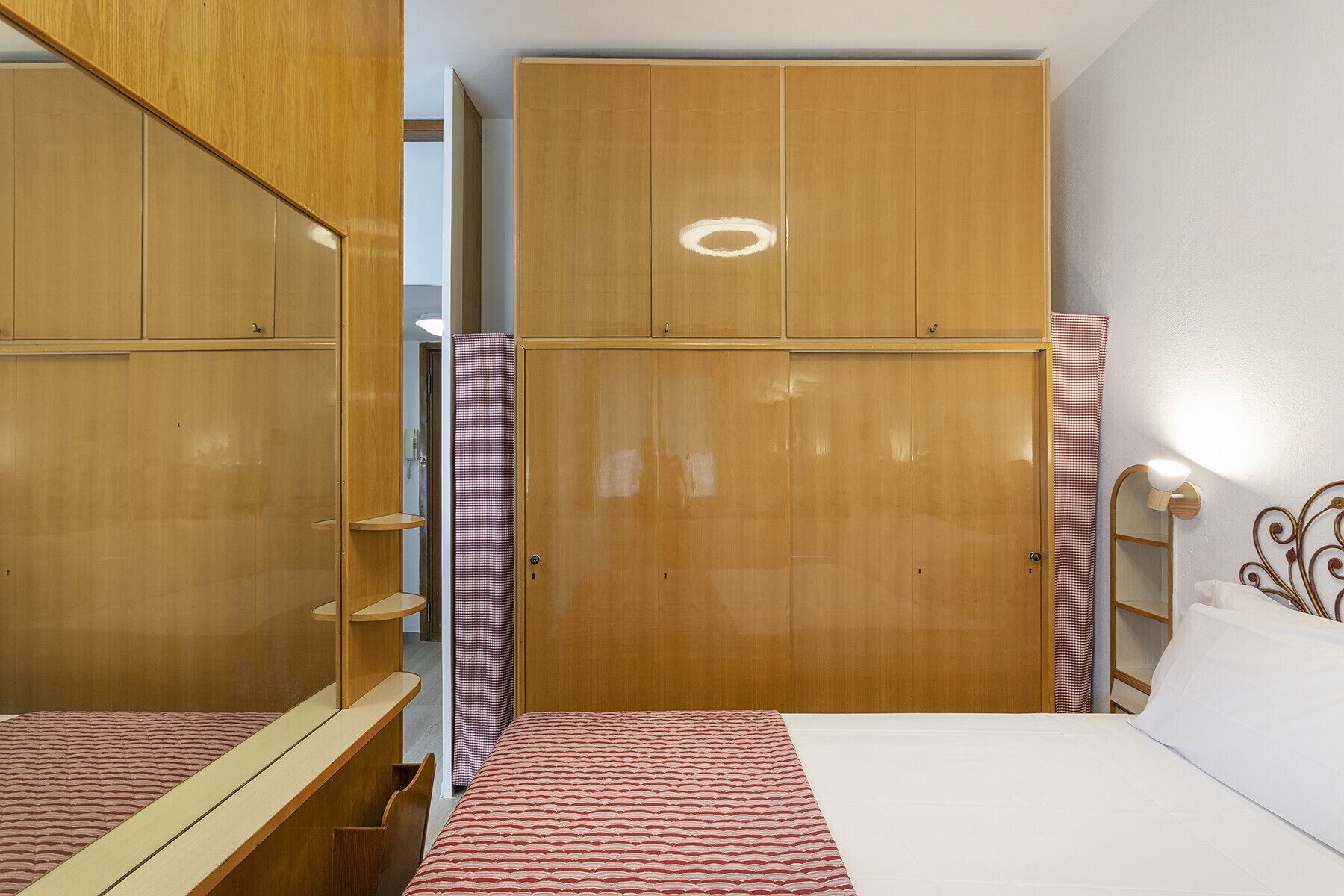 Ein Schlafzimmer mit einem Bett, einem Holzschrank und einem Spiegel.