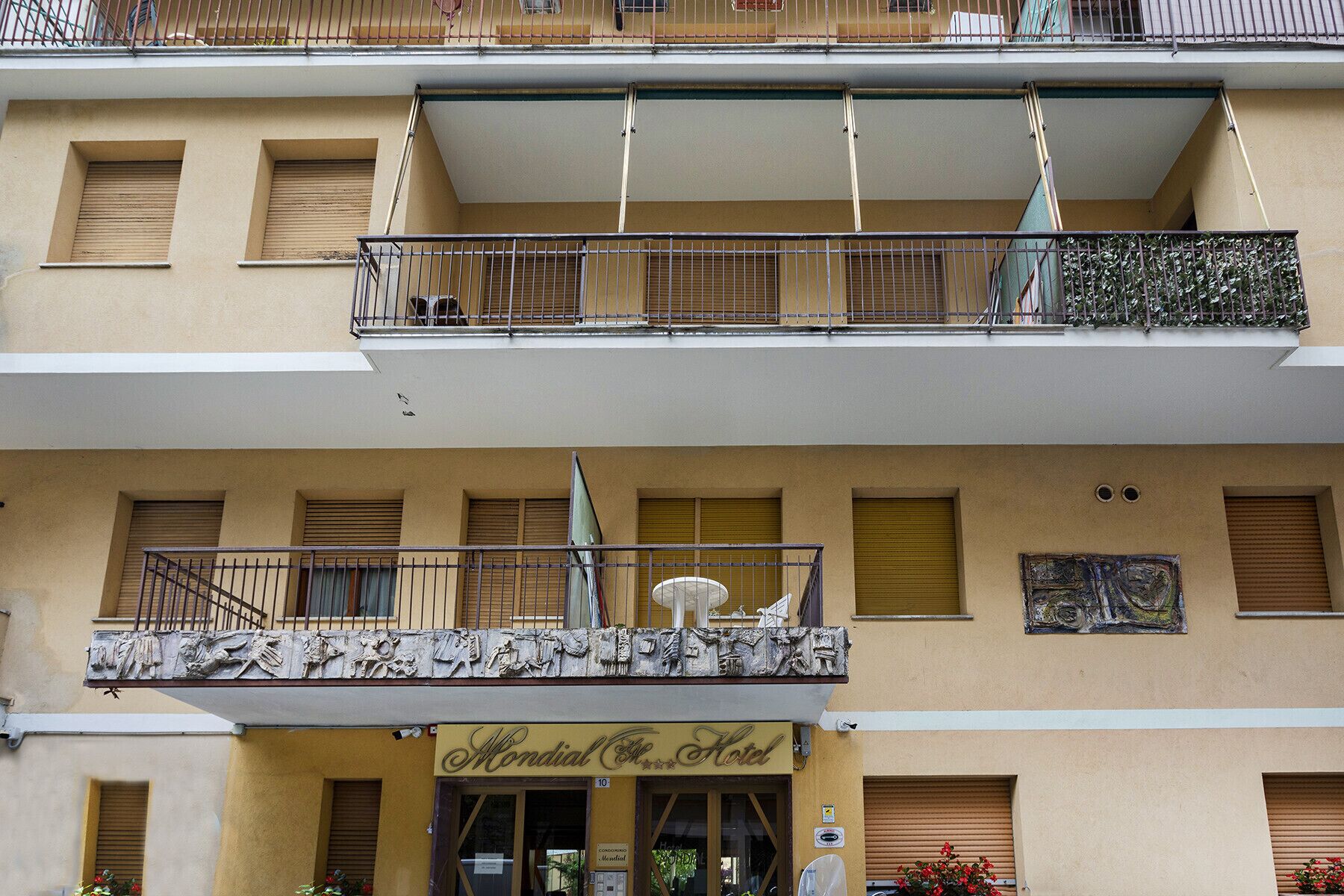 A hotel with a ground-floor entrance, balconies on the upper floors, and a decorative facade.