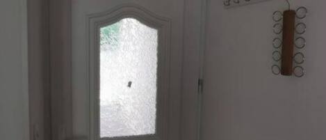 Une porte blanche avec un vitrage dépoli et un porte-manteau fixé au mur, muni de cintres.