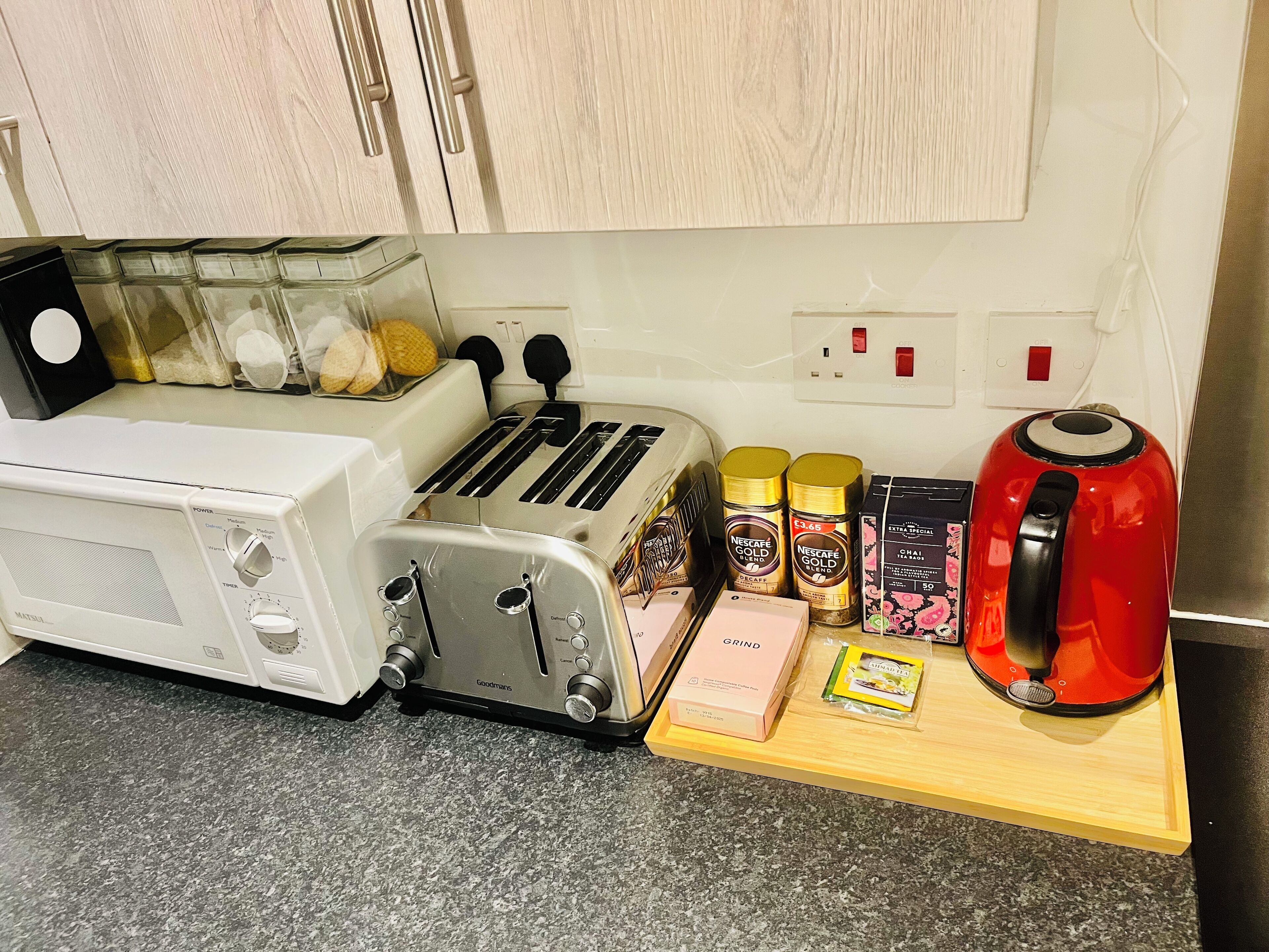A kitchen with a toaster, a kettle, and various coffee products on the counter.