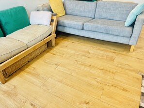 Una sala de estar con un sofá gris, un sillón verde y un banco de madera.