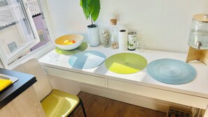 A kitchen with a white countertop, a bowl of fruit, a potted plant, and a water dispenser. - Very Lovely and Central 1-bed Apartment in London (London)