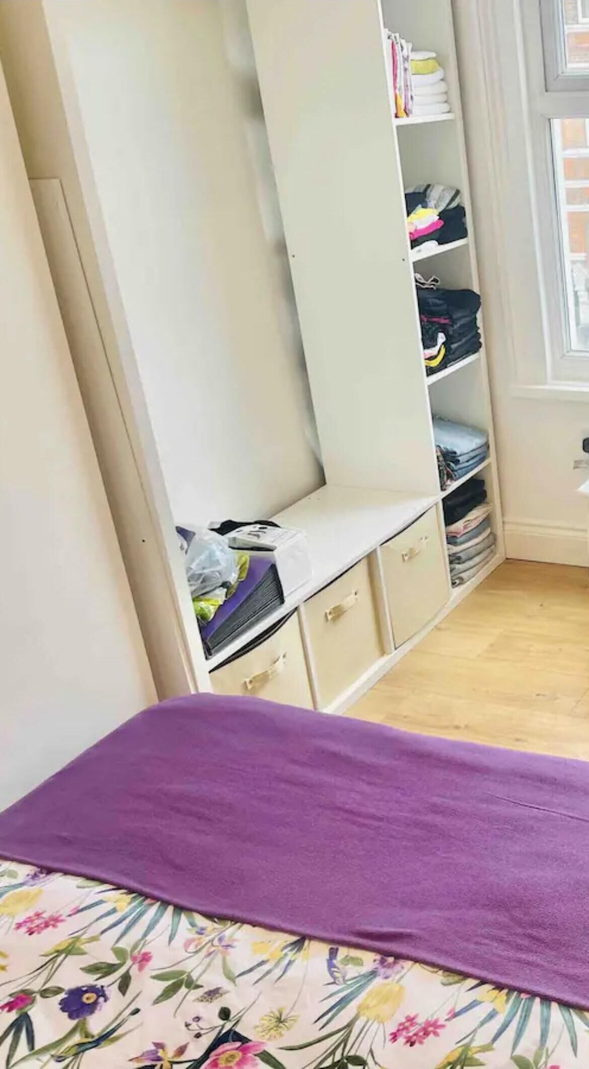 A bedroom with a bed, a wardrobe, and a window.