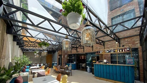 An indoor dining area with tables and chairs, hanging plants, and a bar counter. - About Sololaki (Tbilisi)