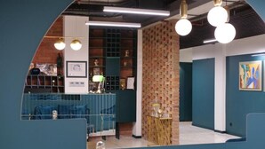 A modern interior with teal walls, a brick accent wall, and a blue sofa. - About Sololaki (Tbilisi)