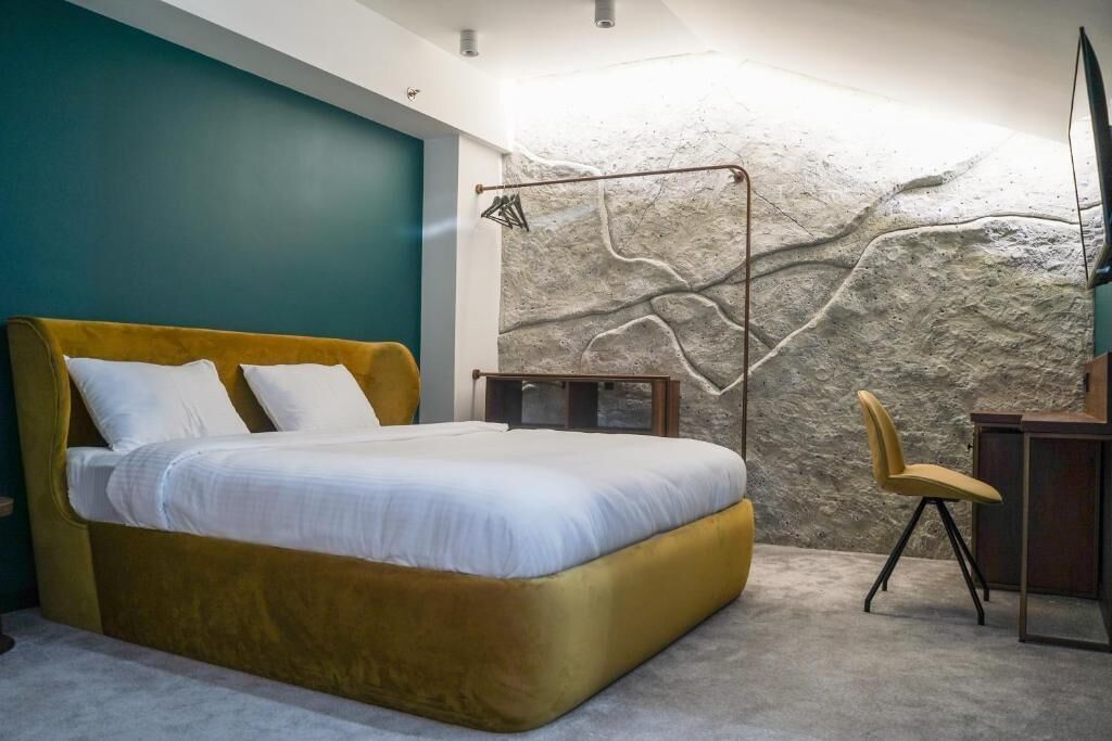 A bedroom with a bed, a desk, and a chair.