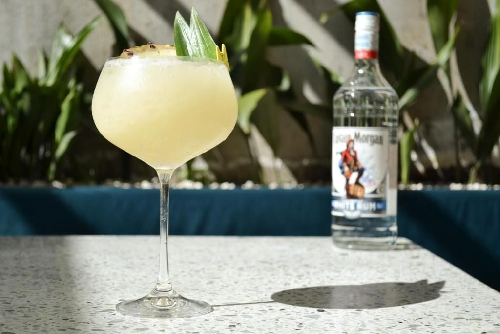 A cocktail in a glass with a bottle of liquor in the background.
