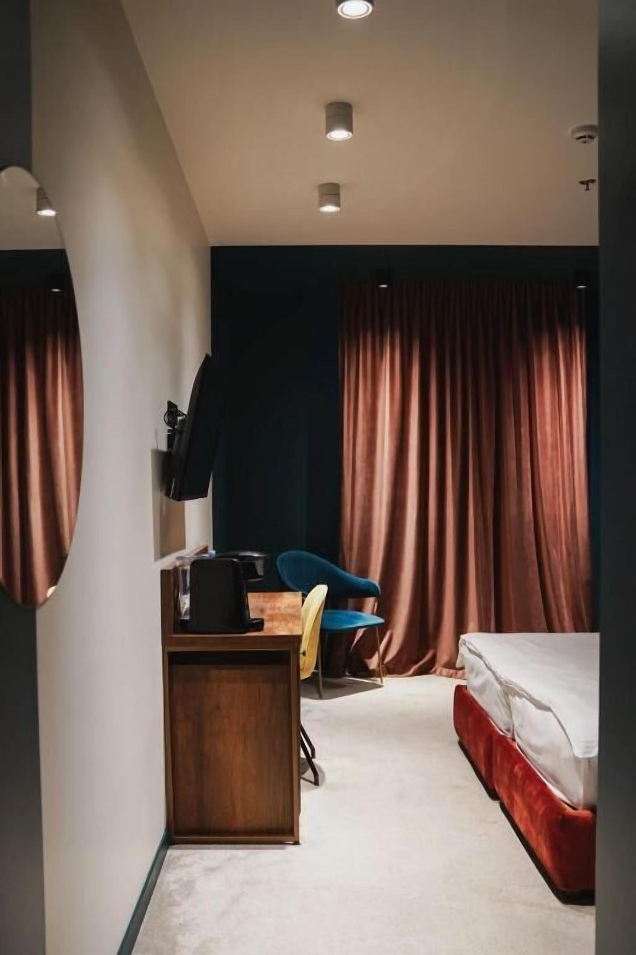 A compact hotel room with a bed, a desk with a chair, and a wardrobe.