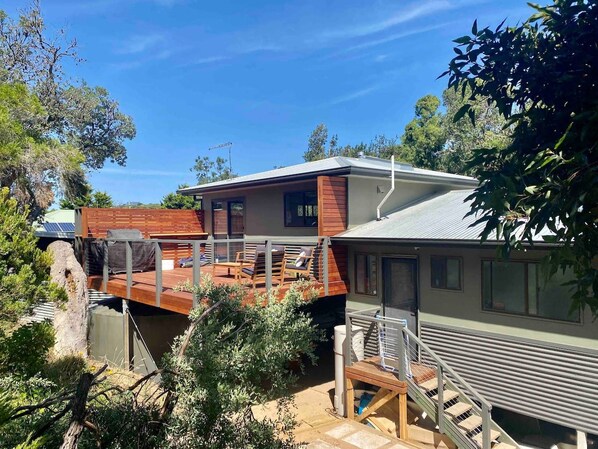 A modern house with a deck, a covered outdoor area, and a large window.