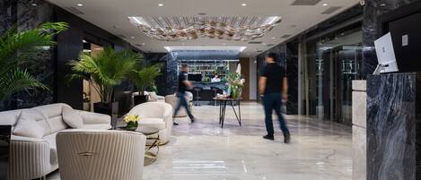 A modern lobby with a reception desk, seating area, and a bar.
