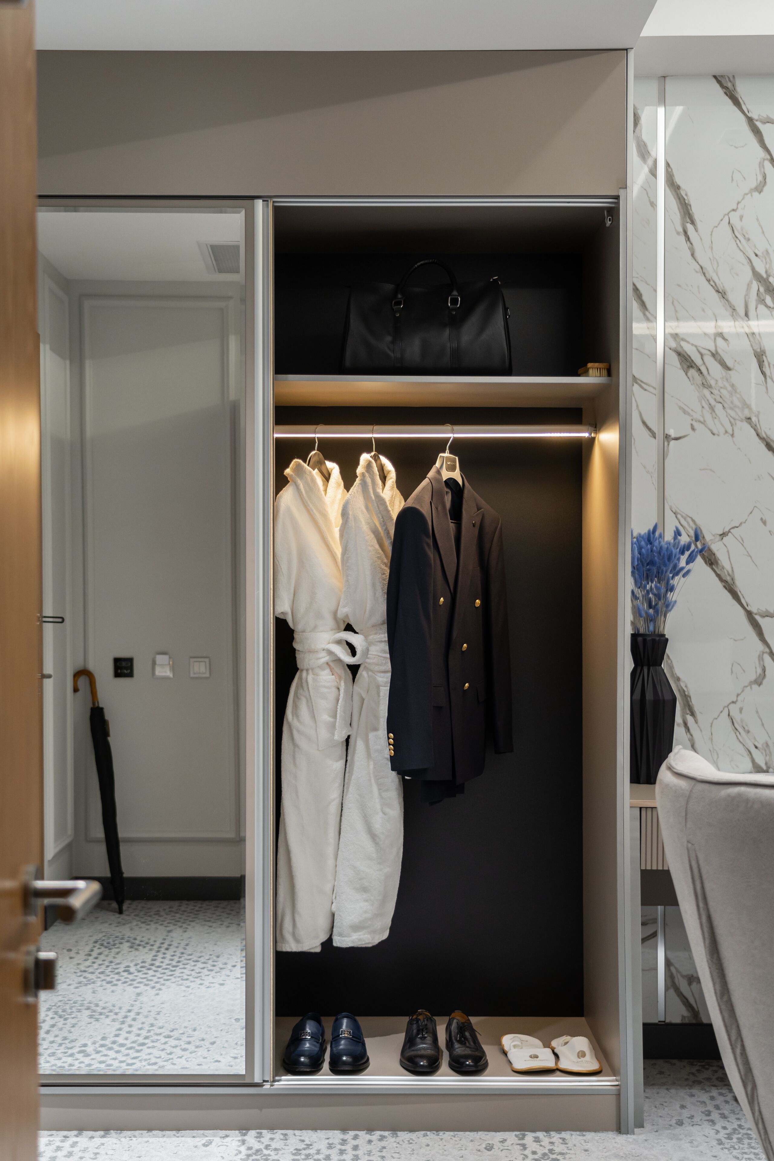 A walk-in closet with hanging robes, a suit, and shoes.
