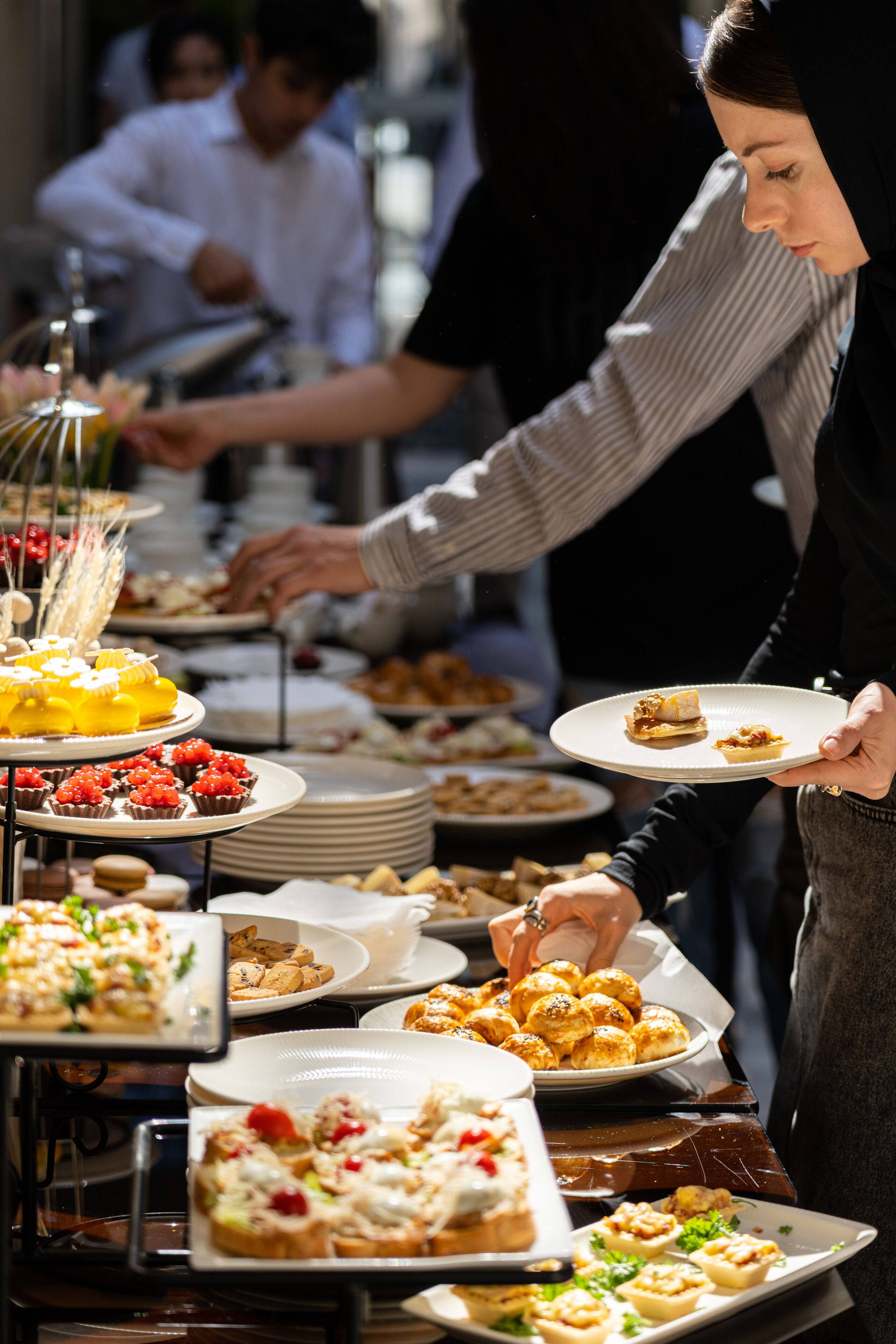 A buffet with various dishes and a person serving food.