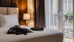 Une chambre d’hôtel avec un grand lit, une table de chevet, une lampe et une vue sur le balcon extérieur.