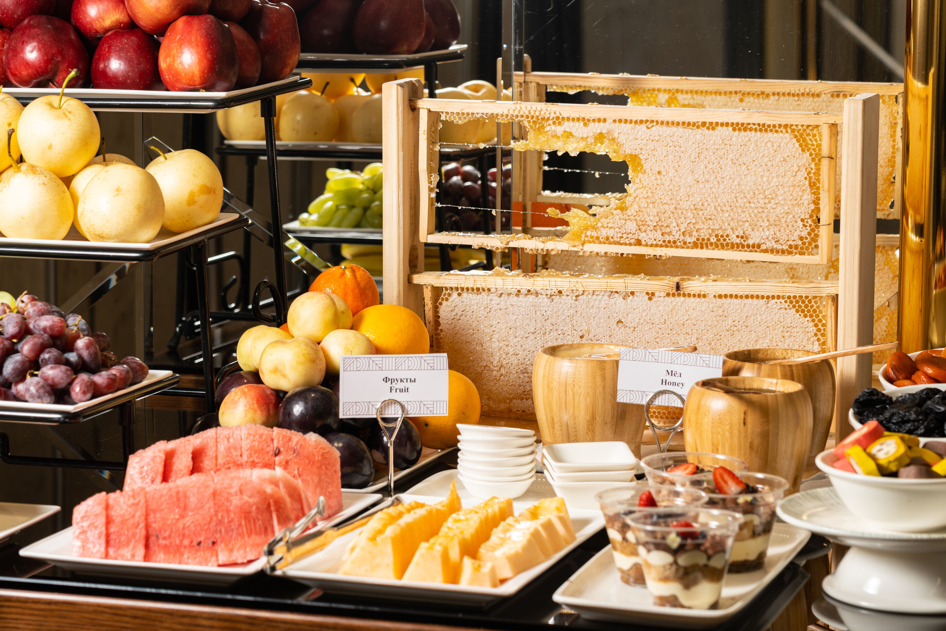 A buffet with various fruits, honey, and desserts.