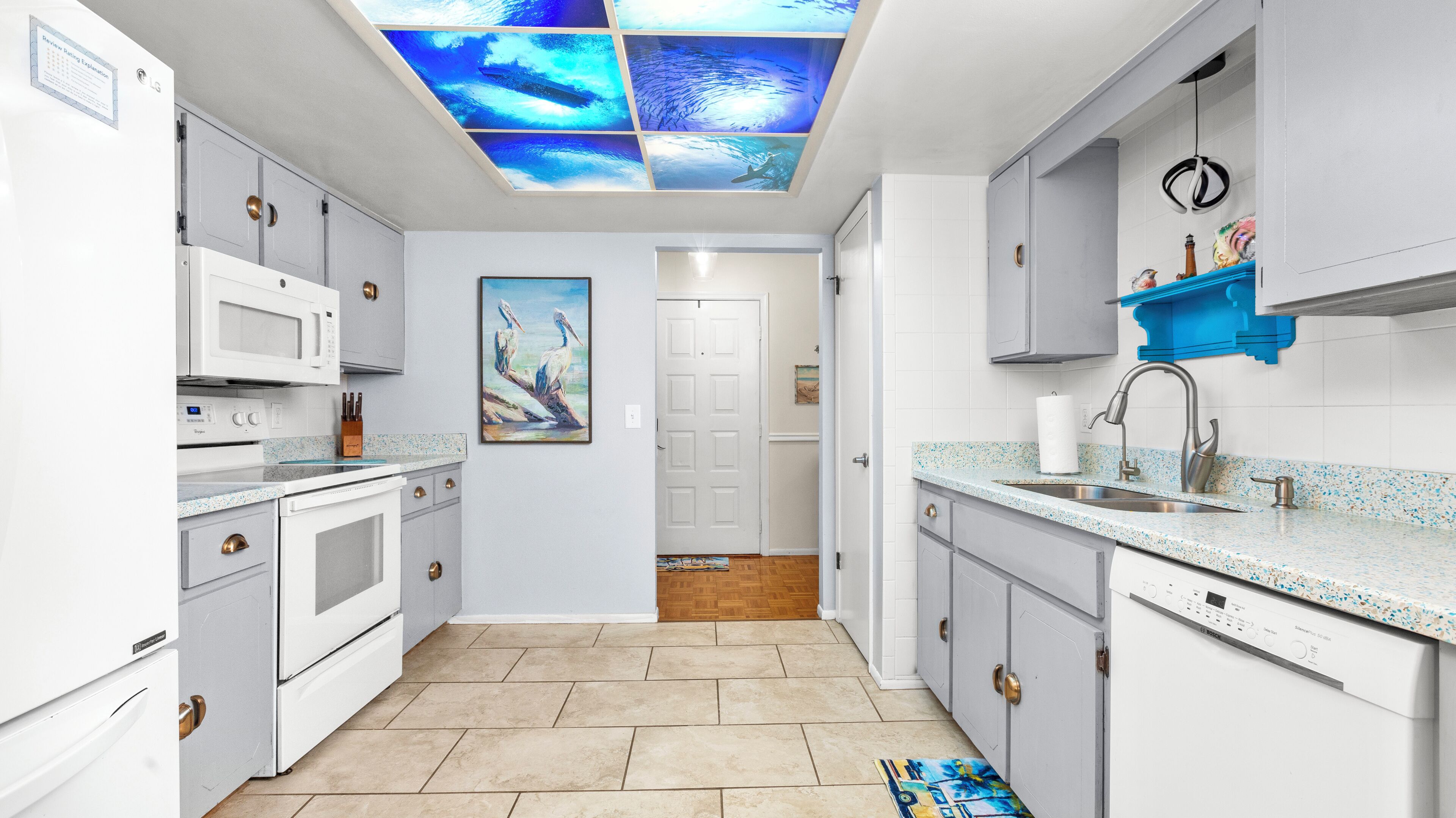 A modern kitchen with white cabinetry, a built-in microwave, and a stainless steel sink.