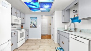 Una cocina moderna con armarios blancos, un microondas integrado y un lavamanos de acero inoxidable.