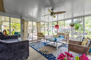 A spacious room with a ceiling fan, large windows, and a variety of seating including a sofa and chairs. - Manatee & kayak friendly waterfront cottage (Ormond Beach)
