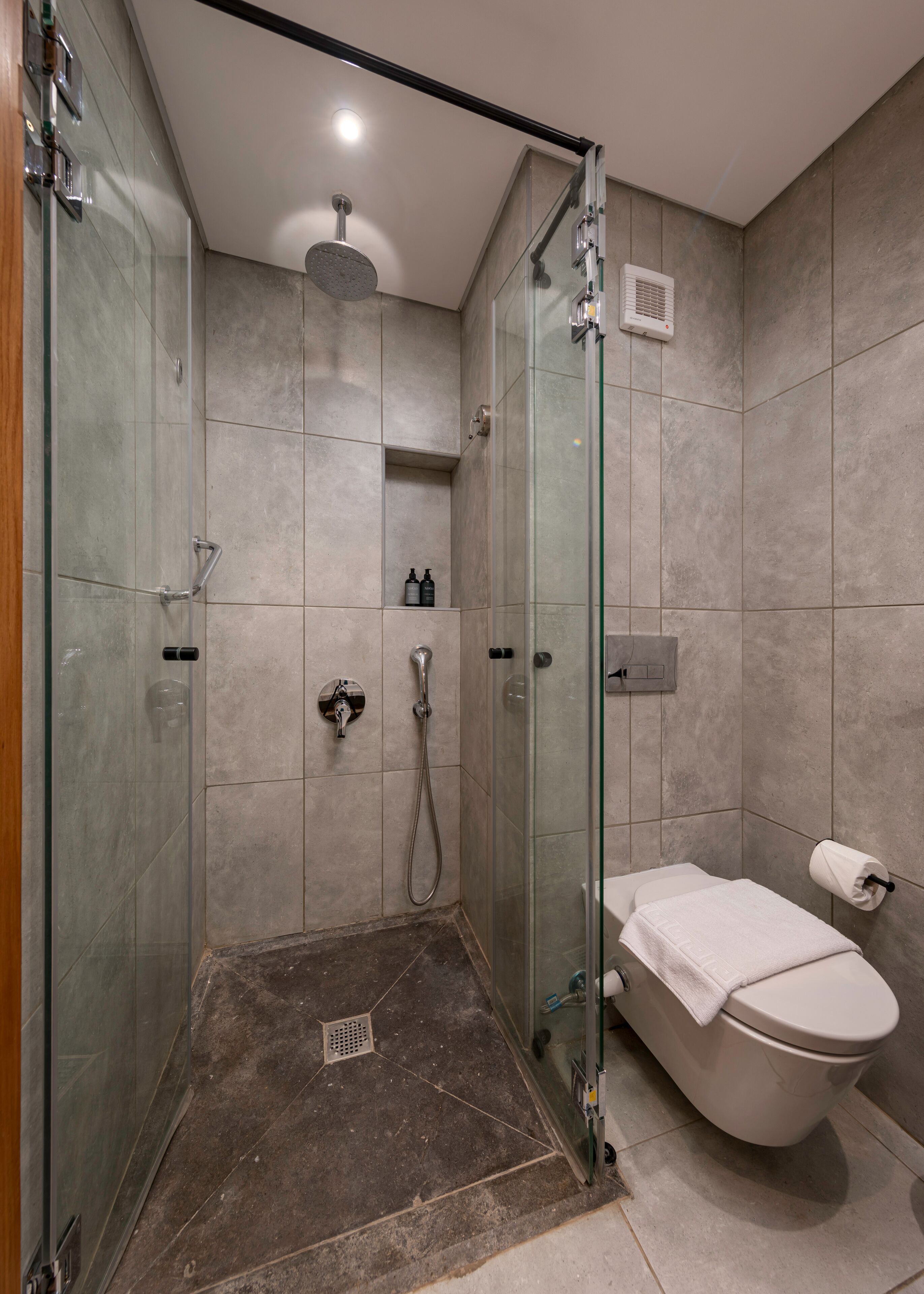 A modern bathroom with a glass-enclosed shower, a toilet, and a sink.