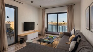 A modern living room with a sofa, a coffee table, a TV, and a balcony with a view of the sea. - Creek Hotel and Residences El Gouna (El Gouna)