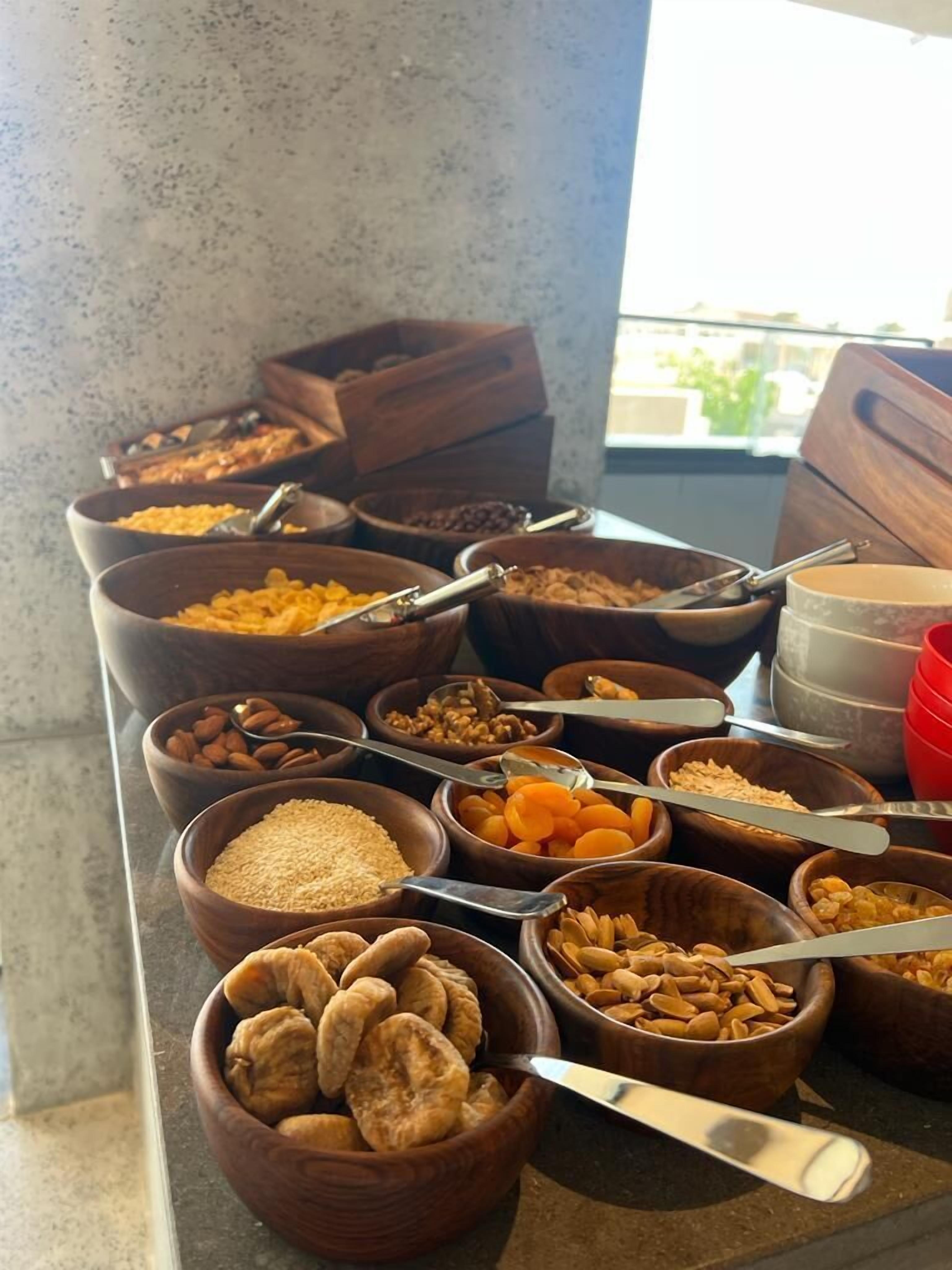 A buffet with various food items in wooden bowls, including nuts, dried fruits, and grains.