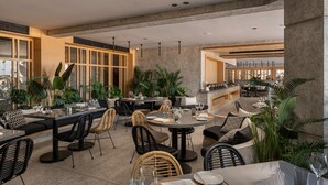 A modern restaurant with round tables, black and white patterned chairs, and abundant indoor plants. - Creek Hotel and Residences El Gouna (El Gouna)