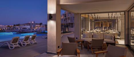 A rooftop pool area with lounge chairs, a bar, and a dining area with tables and chairs.