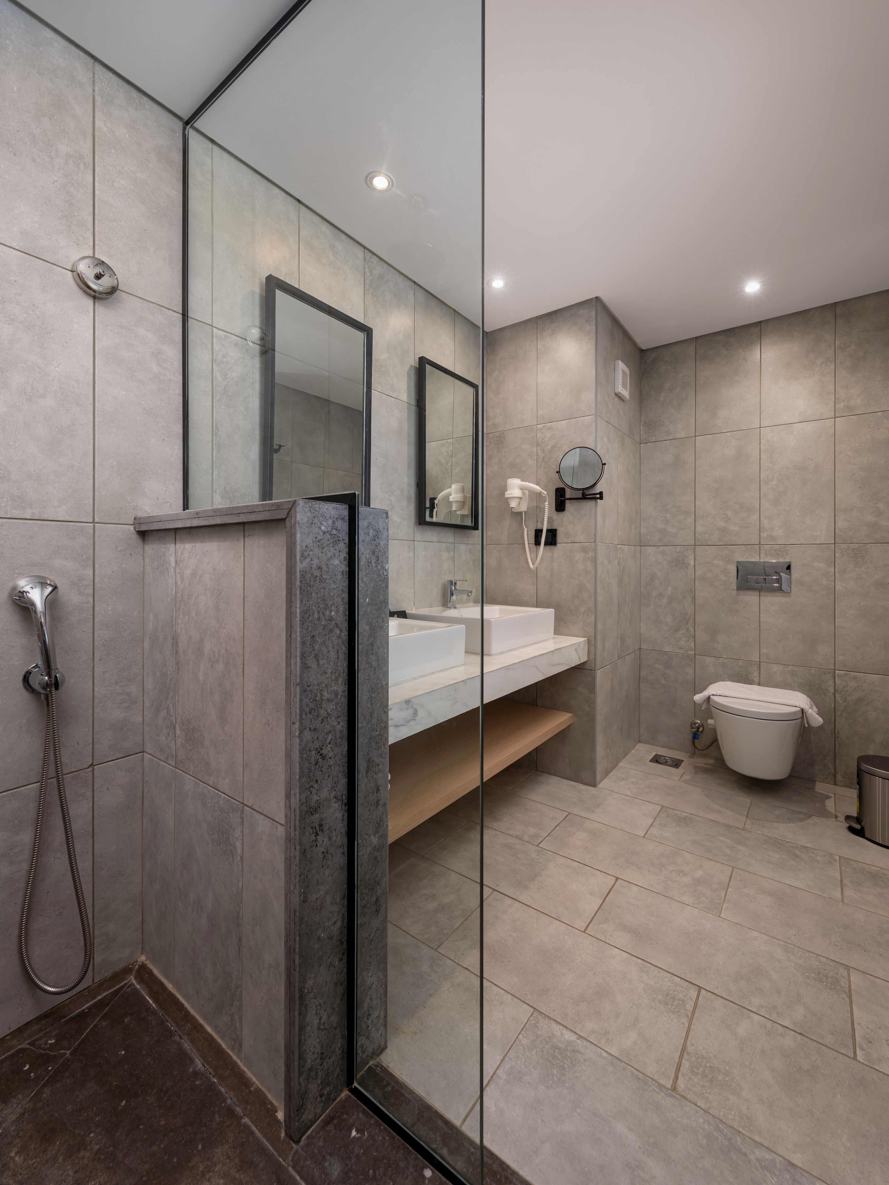 A modern bathroom with a glass shower enclosure, a vanity with a mirror, and a toilet.