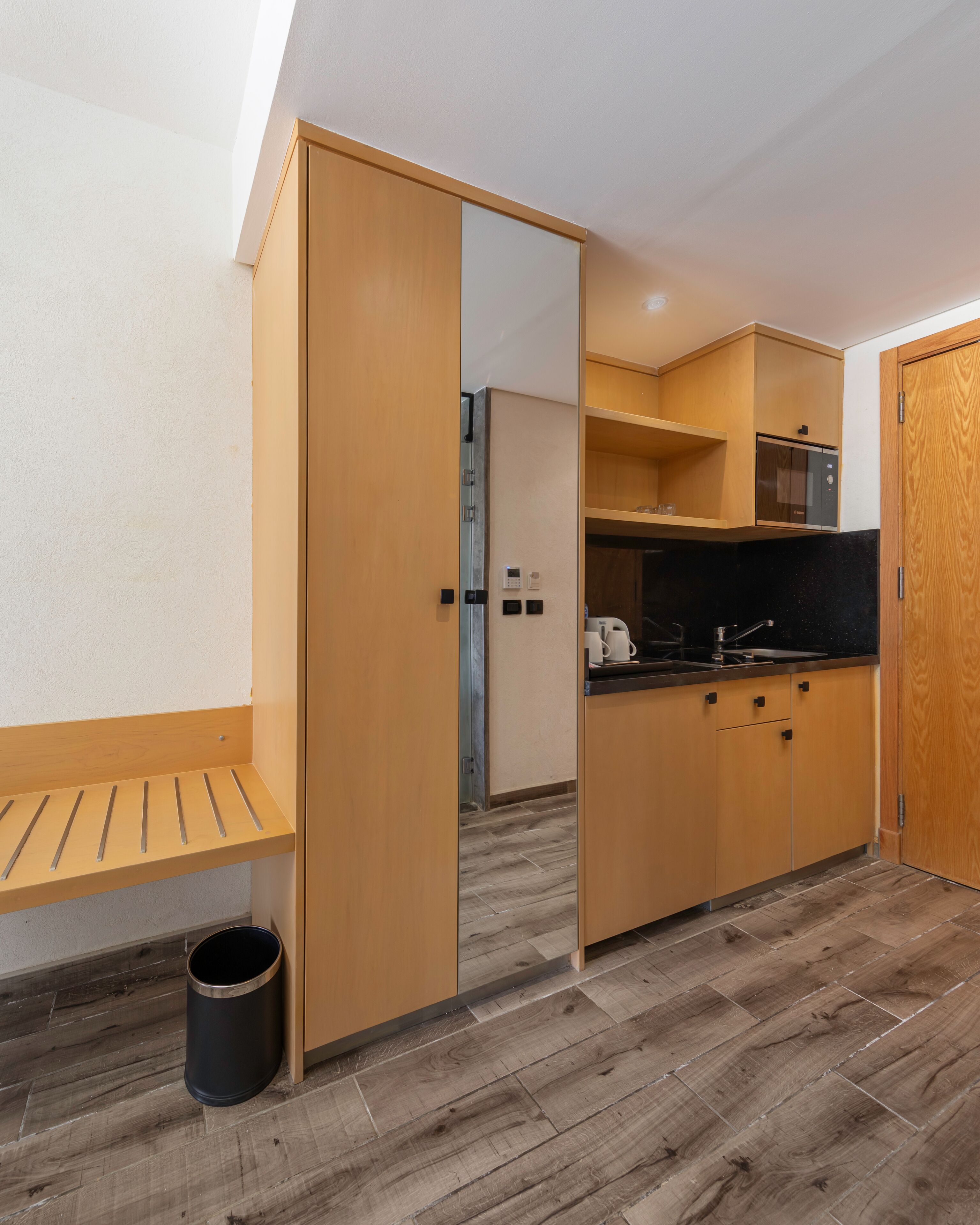 A compact kitchen with wooden cabinets, a built-in oven, and a black countertop.