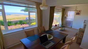 A dining area with a table, chairs, a laptop, and a view of the outdoors.