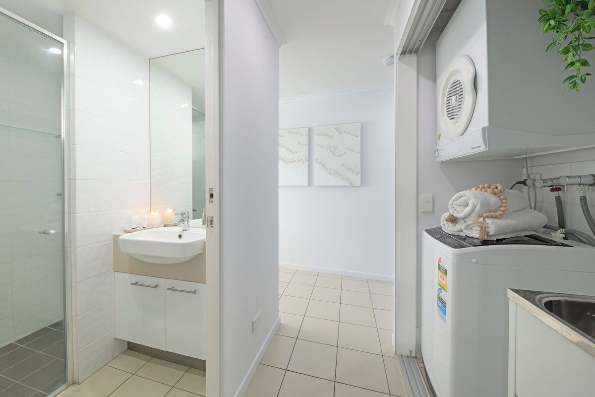 A modern bathroom with a glass shower enclosure, a sink with a mirror, and a towel rack with towels.