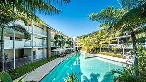 A modern hotel with a swimming pool, balconies, and tropical landscaping. - Epitome of luxury - absolute waterfront penthouse (Cannonvale)