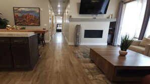 A modern kitchen with dark cabinetry, a wooden island, and a large painting of a desert landscape.