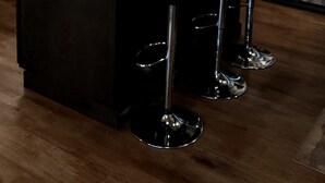 A modern kitchen with dark wood cabinets, a stainless steel refrigerator, a microwave, and a wooden island with bar stools.