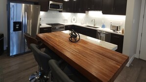 A modern kitchen with dark cabinets, stainless steel appliances, a wooden island, and bar stools. - SageCreek "Moab" Hot Tubs Heated Pool - Condo D3 (Moab)