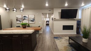 Una cocina moderna con una isla central, comedor y sala de estar con chimenea.